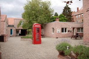 an old red phone booth in a courtyard at Room in Apartment - Condo Gardens Leuven - Student Studio Single in Leuven