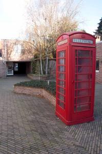 una cabina telefonica rossa seduta su una strada di mattoni di Room in Apartment - Condo Gardens Leuven - Student Studio Single a Lovanio