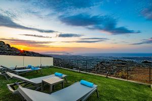 a patio with a view of the ocean at sunset at Villa Mari Chania, with private ecologic pool and amazing view! in Chania Town +89 photos