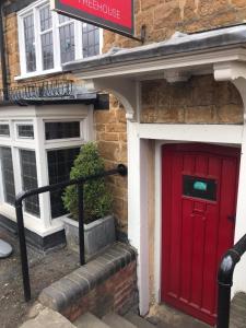 una puerta roja en el lateral de un edificio de ladrillo en The Three Pigeons Inn en Banbury