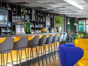イエールにあるメルキュール イエール サントル コート ダ ジュールのレストランの黄色と青の椅子付きのバー