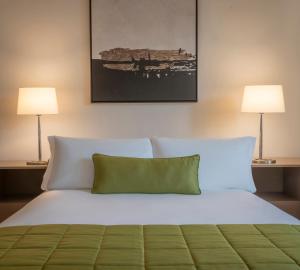 a bedroom with a bed with white sheets and two lamps at The Gibson Hotel in Dublin