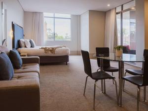 a hotel room with a couch and a table and a bed at Mercure Centro Port Macquarie in Port Macquarie