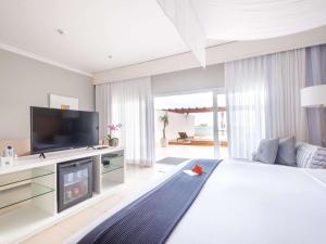 una camera da letto con un grande letto bianco e una televisione di Hotel Jequitimar Guaruja Resort & Spa by Accor - Ex Sofitel a Guarujá