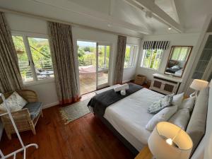a bedroom with a bed and a couch and windows at Baha Sanctuary House - 3 Bedroom House with Pool in Plettenberg Bay