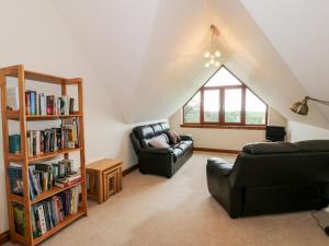 a living room with two chairs and a book shelf at Cairnhapple House in Stranraer