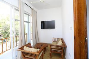 a living room with two chairs and a tv on the wall at IMARA VILLA 