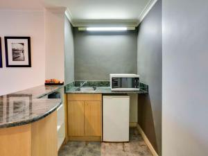 a kitchen with a sink and a microwave on a counter at Mercure North Melbourne in Melbourne