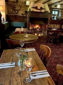 a table with wine glasses and a fireplace in a restaurant at Farmyard Inn in Youlgreave