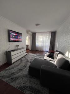 sala de estar con sofá y TV de pantalla plana en Двокімнатні апартаменти в парковій зоні ,два великих Смарт TV, преміум підписки, en Krivoy Rog