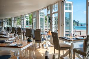 a restaurant with tables and chairs and windows at South Sands Hotel in Salcombe