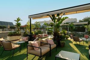 eine Terrasse mit Stühlen und Tischen auf dem Dach in der Unterkunft Hilton Garden Inn Sevilla in Sevilla