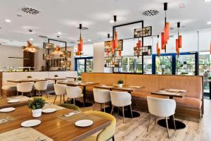 een restaurant met houten tafels, stoelen en ramen bij Hilton Garden Inn Sevilla in Sevilla