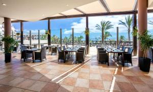a restaurant with tables and chairs and a view of the ocean at Occidental Jandía Mar in Morro del Jable