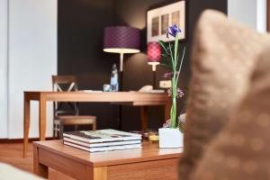 a table with books and a vase with a flower on it at Dorint Hotel am Dom Erfurt in Erfurt