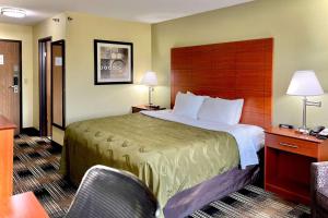 a hotel room with a large bed and two chairs at Quality Inn & Suites Wisconsin Dells Downtown - Waterparks Area in Wisconsin Dells