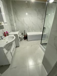 ein weißes Bad mit einem Waschbecken und einer Dusche in der Unterkunft Двухкомнатные бизнес апартаменты в ЖК Томирис in Atyrau