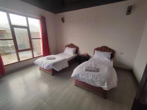 um quarto com duas camas e uma janela em Stone rest house jebel shams em Al Hamra