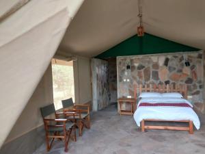 a bedroom with a bed and a table and chairs at Resian Mara Camp in Talek