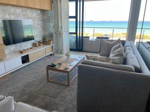 a living room with a couch and a tv and a table at Blouberg Luxury Beachfront Apartment in Bloubergstrand