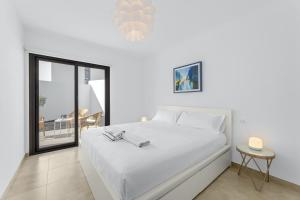 a white bedroom with a bed and a balcony at Casahost Fontaine Bleue Villa in Tías +22 photos