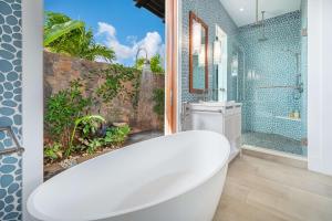 a white bath tub in a bathroom with a shower at Kauai Luxury Vacation Villas in Koloa