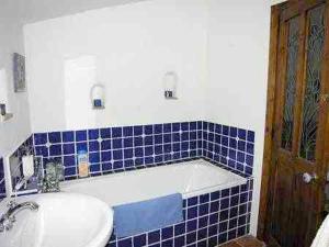 baño con lavabo y pared de azulejos azules en Beautifully renovated village house with spectacular views, en Canillas de Albaida
