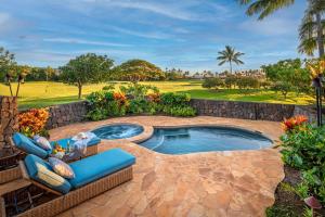 a swimming pool with a patio furniture and a rock wall at Kauai Luxury Vacation Villas in Koloa