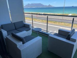 een kamer met 2 banken en uitzicht op de oceaan bij Blouberg Luxury Beachfront Apartment in Bloubergstrand