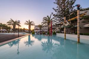 - une piscine dans un complexe avec des palmiers dans l'établissement D'Andrea Mare Beach Hotel, à Ialyssos