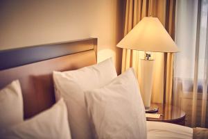 a bed with white pillows and a table with a lamp at Hotel Nassauer Hof in Wiesbaden