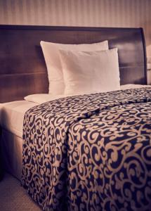 a bed with a black and white blanket and pillows at Hotel Nassauer Hof in Wiesbaden