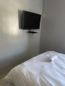 a bedroom with a bed with a flat screen tv on the wall at Stay Inn Lodge Boksburg in Boksburg