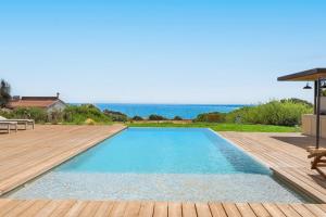 a swimming pool with a wooden deck and the ocean at Al Nair in Marina di Modica