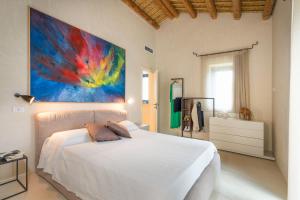 a bedroom with a white bed and a painting on the wall at Al Nair in Marina di Modica