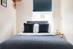 a bedroom with a bed with blue pillows and a window at CitySpace Borough in London