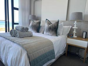 Blouberg Luxury Beachfront Apartment في بلوبيرجستراند: غرفة نوم عليها سرير وفوط