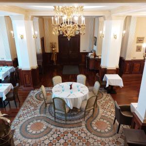 une salle à manger avec une table, des chaises et un lustre dans l'établissement Castle Garden ***, à Szombathely