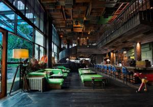 a restaurant with green couches and tables and windows at The Orient Jakarta, a Royal Hideaway Hotel in Jakarta