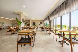 een restaurant met tafels en stoelen en grote ramen bij Ramada by Wyndham Cesme in Çeşme