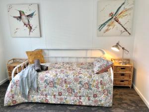 a bedroom with a bed with a floral bedspread at The Corner Cottage Orbost in Orbost