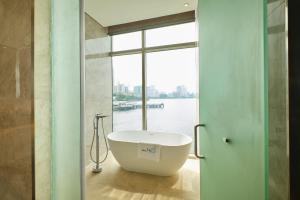 a bathroom with a bath tub in front of a window at Hotel H2O in Manila