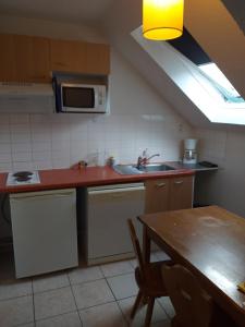 a kitchen with a sink and a microwave and a table at Appartement F2 au domaine des 100 lacs - piscine - sauna - hammam in Cauterets