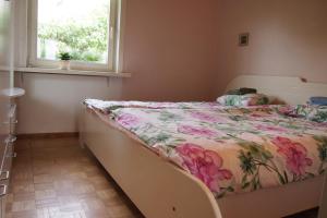 1 dormitorio con 1 cama con colcha de flores y ventana en Männi Holiday House en Haapsalu