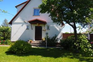 a white house with a tree in the yard at Männi Holiday House in Haapsalu