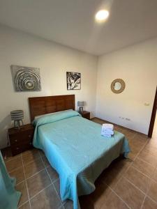 a bedroom with a bed with a blue comforter at Chalet. Jardín, vistas, tranquilidad in Caleta de Interián