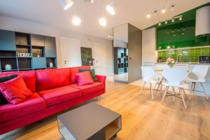 a living room with a red couch and a kitchen at SPA Waterlane Island Deluxe 2 by Grand Apartments in Gdańsk