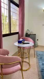 ein Wohnzimmer mit 2 rosa Stühlen und einem Tisch in der Unterkunft Arabian Nights Nook in Muscat