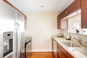 a kitchen with a stainless steel refrigerator and wooden cabinets at Foggy Bottom 1br w wd pool gym nr Georgetown WDC-658 in Washington, D.C.