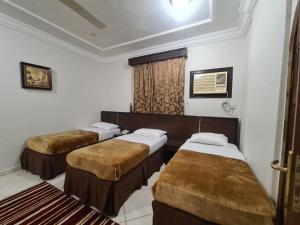 een kamer met 3 bedden en een raam bij شقق درة الصالحين in Mekka